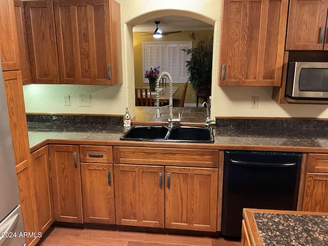 kitchen with dark countertops, black dishwasher, stainless steel microwave, and a sink