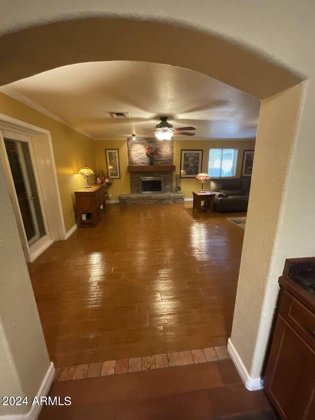 unfurnished living room with a large fireplace, visible vents, baseboards, wood-type flooring, and ceiling fan