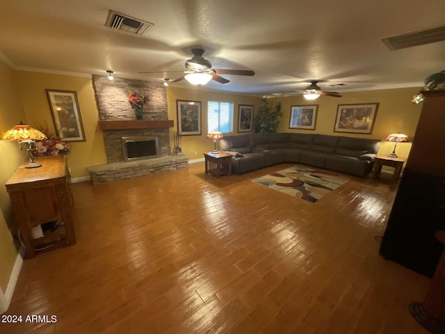 living room with hardwood / wood-style flooring, a fireplace, visible vents, and crown molding