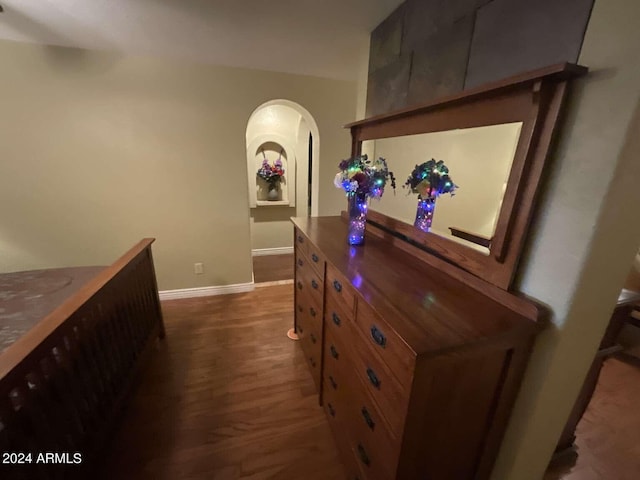 hall with baseboards, arched walkways, and dark wood finished floors