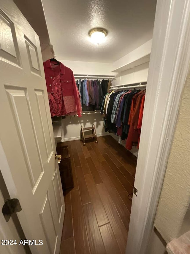 walk in closet with dark wood-style flooring