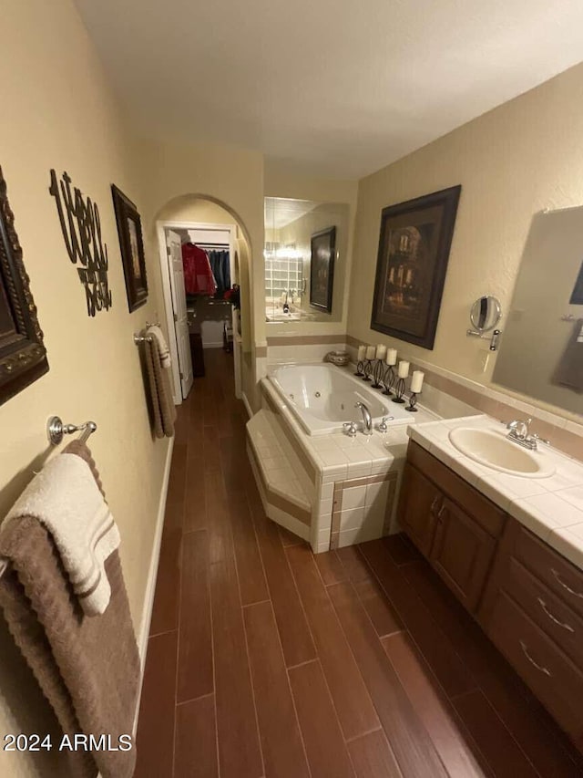 full bathroom featuring a jetted tub, wood finished floors, and vanity