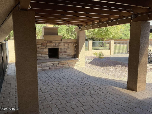 view of patio with an outdoor stone fireplace and fence