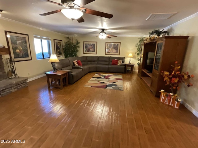 living area with visible vents, crown molding, baseboards, and wood finished floors