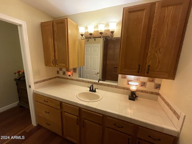 bathroom featuring wood finished floors, backsplash, and vanity