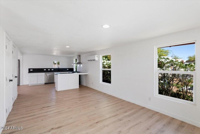 kitchen featuring light hardwood / wood-style flooring, wall chimney exhaust hood, and white cabinetry