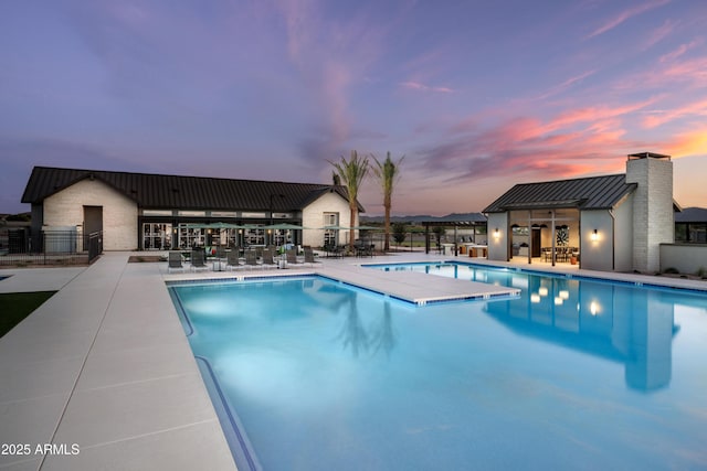 pool at dusk with a patio area