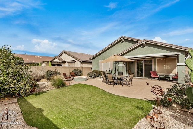 back of property featuring a patio, a fire pit, and a lawn