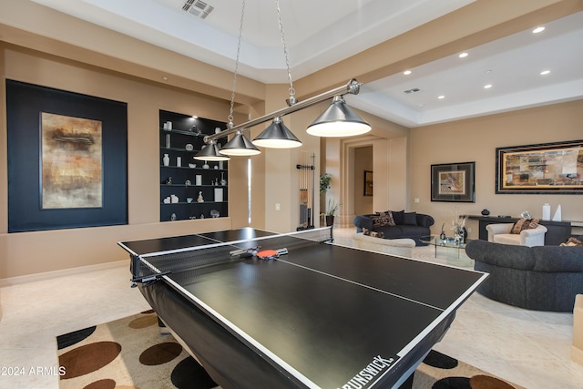 recreation room with built in shelves and a raised ceiling