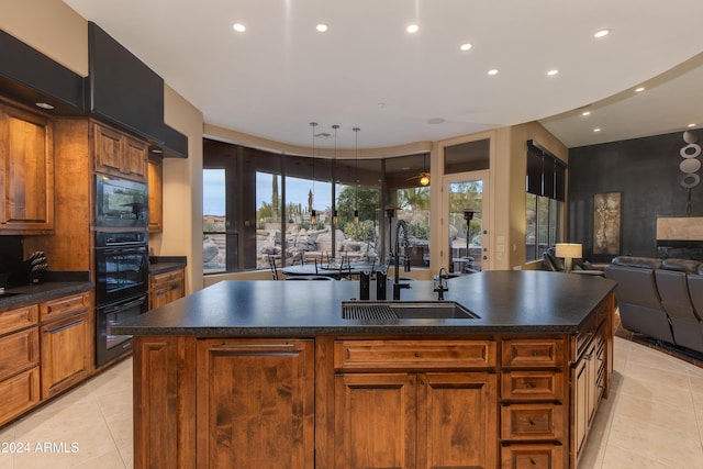 kitchen featuring black appliances, sink, light tile patterned floors, and a kitchen island with sink