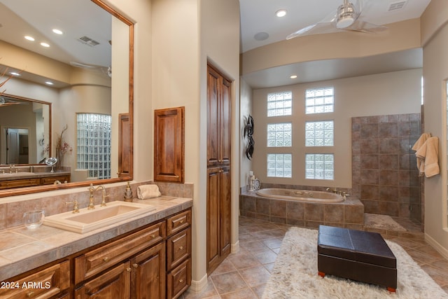 bathroom featuring tile patterned floors, vanity, ceiling fan, and tiled tub