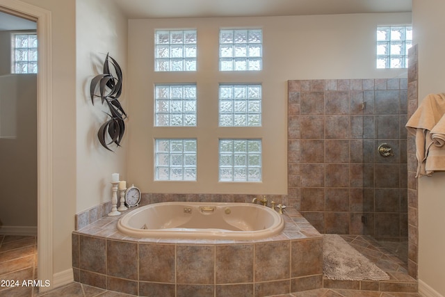 bathroom featuring tile patterned floors, tiled bath, and a wealth of natural light