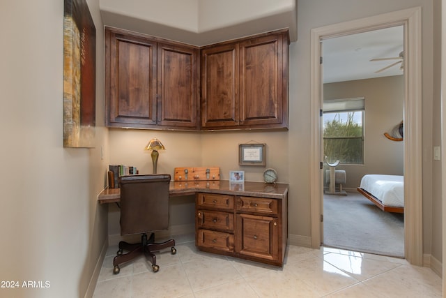 office area with light tile patterned floors, built in desk, and ceiling fan