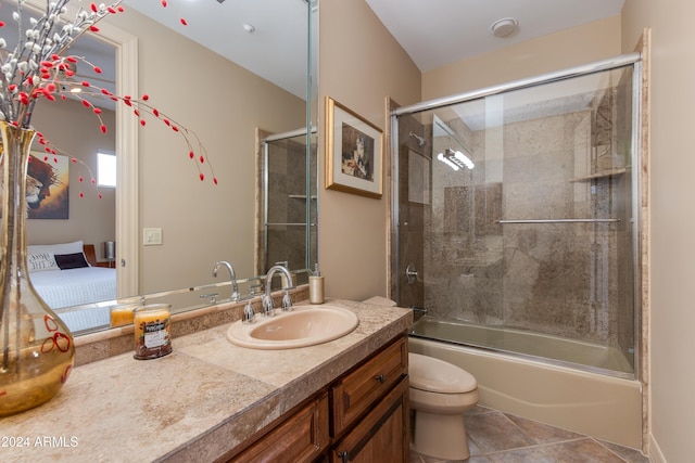 full bathroom with shower / bath combination with glass door, tile patterned floors, vanity, and toilet