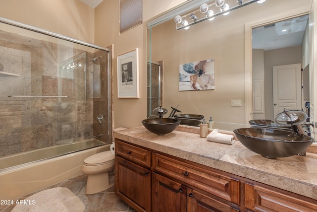 full bathroom featuring tile patterned floors, vanity, toilet, and bath / shower combo with glass door