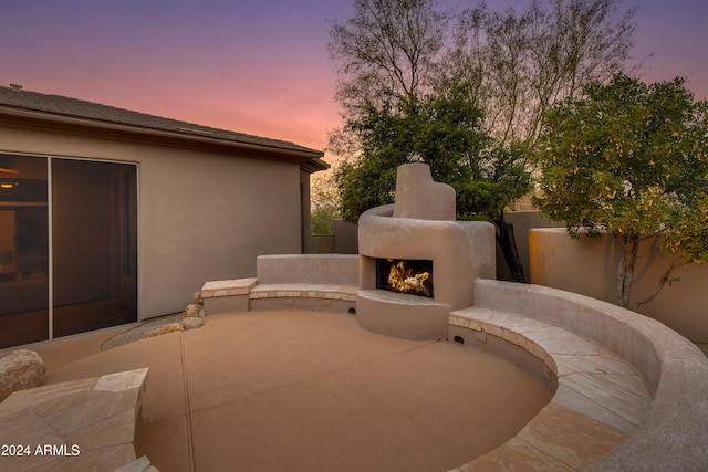 patio terrace at dusk with an outdoor fireplace