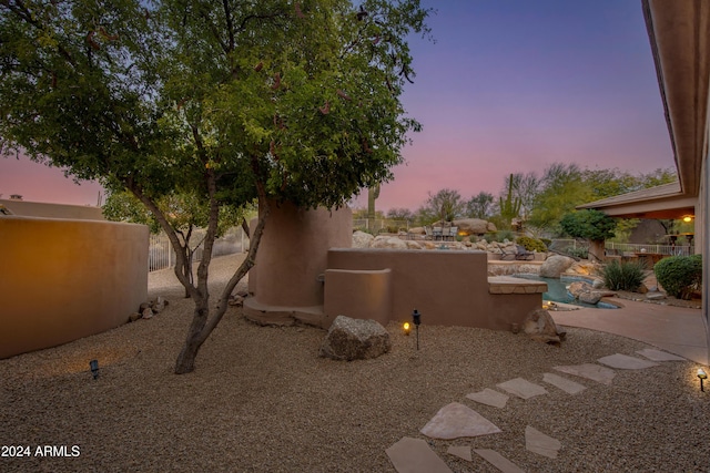 property exterior at dusk featuring a patio area and a swimming pool