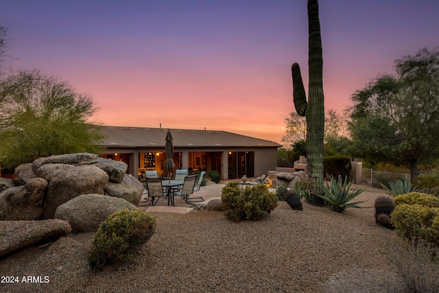 back house at dusk featuring a patio