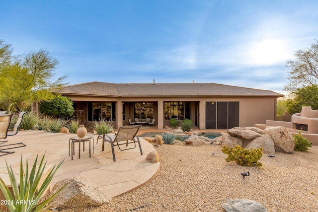 rear view of property with a pool with hot tub, a fireplace, and a patio