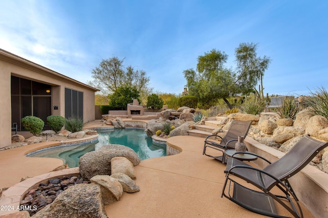 view of swimming pool featuring pool water feature, a patio area, and exterior fireplace