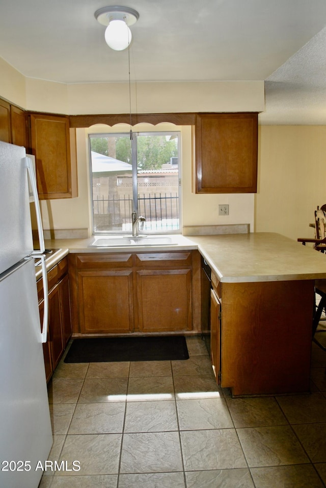 kitchen featuring sink, kitchen peninsula, and white refrigerator