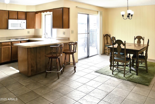 kitchen with a kitchen bar, sink, decorative light fixtures, a chandelier, and kitchen peninsula