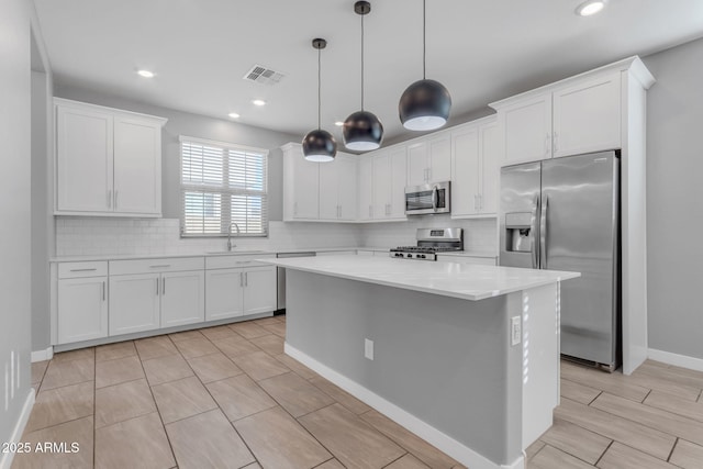 kitchen with appliances with stainless steel finishes, a center island, sink, and white cabinets