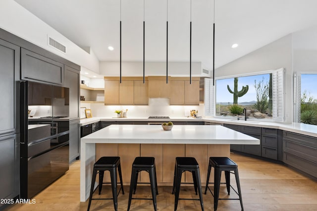 10875 E Mirasol Cir, Scottsdale, AZ 85255 - kitchen with a breakfast bar area, open shelves, a sink, and light wood-style flooring