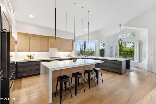 10875 E Mirasol Cir, Scottsdale, AZ 85255 - kitchen with stainless steel gas stovetop, a kitchen bar, a center island, light countertops, and light wood-style floors