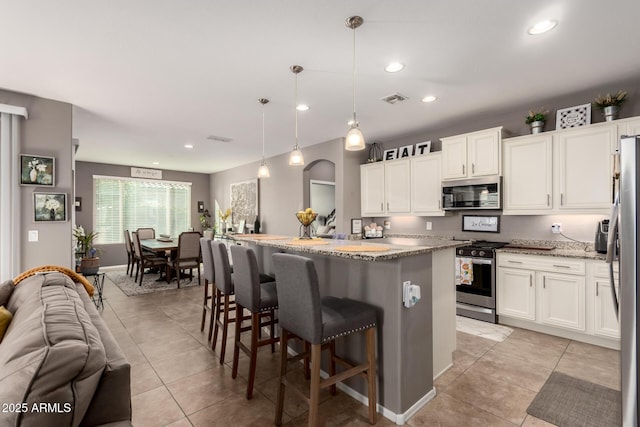 kitchen featuring pendant lighting, white cabinetry, a kitchen island, and appliances with stainless steel finishes