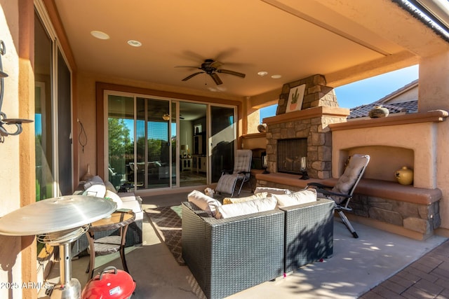 view of patio / terrace featuring ceiling fan and an outdoor living space with a fireplace