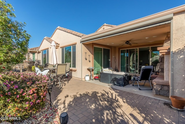 back of property featuring ceiling fan and a patio