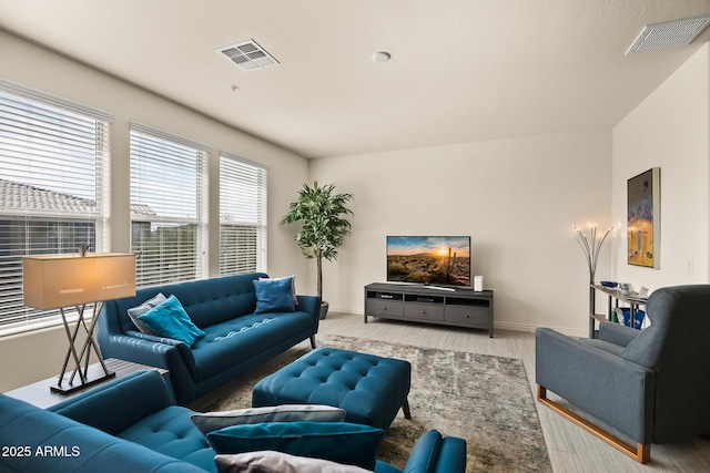 living area featuring light wood-style floors, visible vents, and baseboards