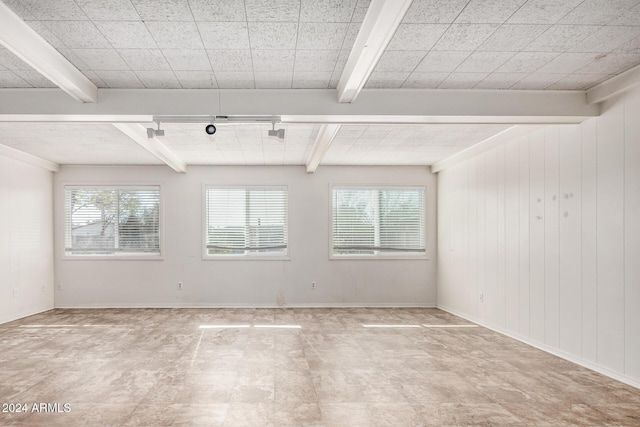 spare room featuring beam ceiling and wooden walls