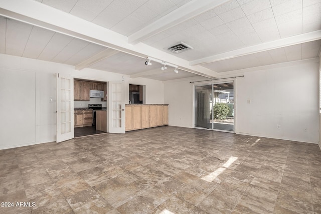 unfurnished living room with beam ceiling and french doors