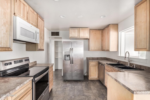 kitchen with light brown cabinetry, stainless steel appliances, and sink