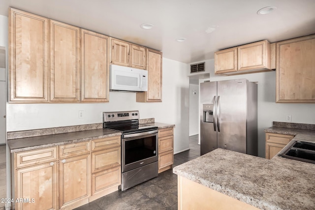 kitchen with dark tile patterned flooring, light brown cabinetry, sink, and appliances with stainless steel finishes