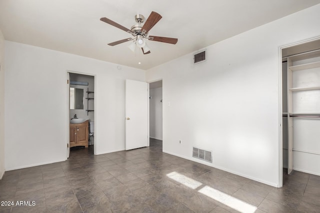 unfurnished bedroom with ceiling fan, ensuite bathroom, sink, and a closet