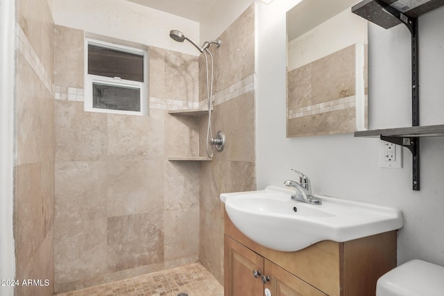 bathroom featuring a tile shower, vanity, and toilet