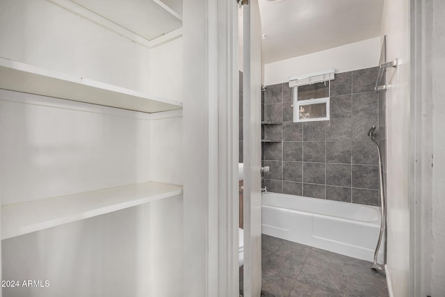 bathroom with toilet and tiled shower / bath