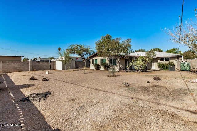 back of house with a storage unit and central AC