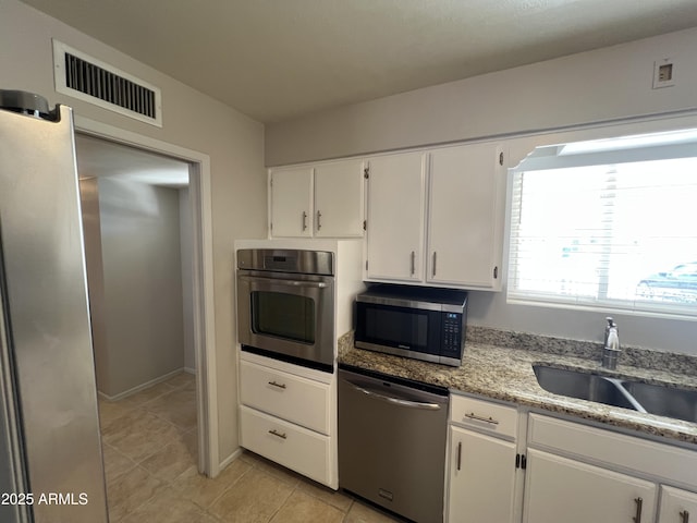 5342 E Des Moines St, Mesa, AZ 85205 - kitchen featuring appliances with stainless steel finishes, white cabinetry, a sink, light tile patterned floors, and light stone counters