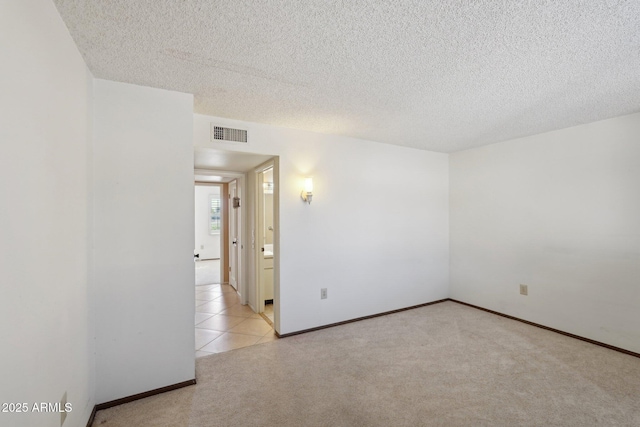 unfurnished room with light colored carpet and a textured ceiling