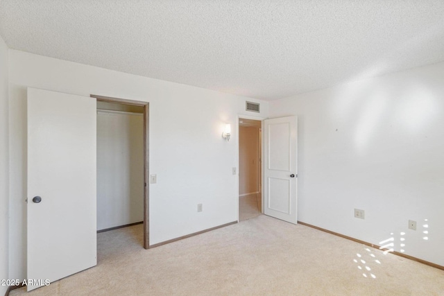 unfurnished bedroom with a textured ceiling, light carpet, and a closet