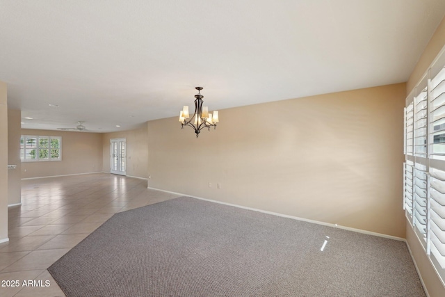 tiled empty room with ceiling fan with notable chandelier