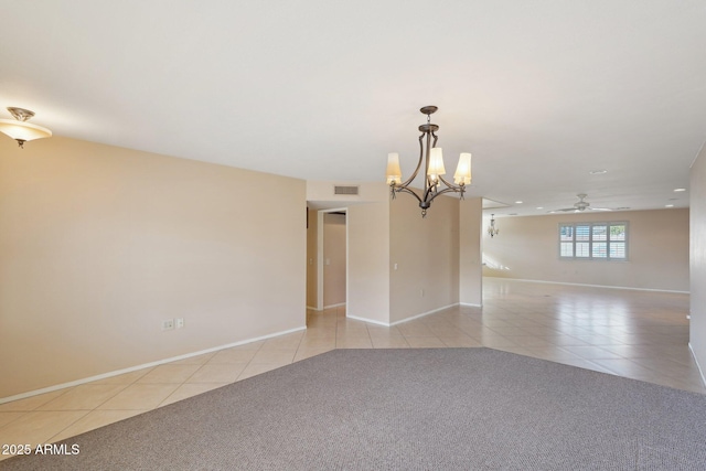 tiled spare room with ceiling fan with notable chandelier