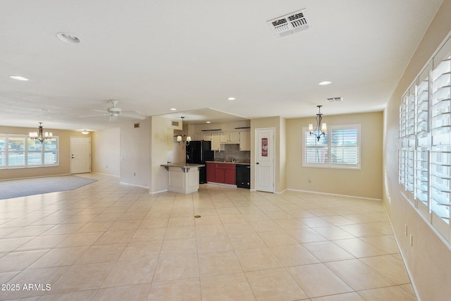 unfurnished living room with ceiling fan with notable chandelier and light tile patterned flooring