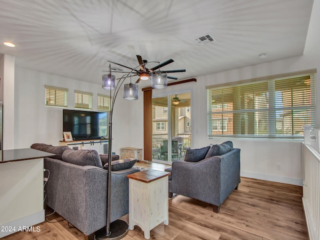 living room featuring wood-type flooring, ceiling fan, and a healthy amount of sunlight