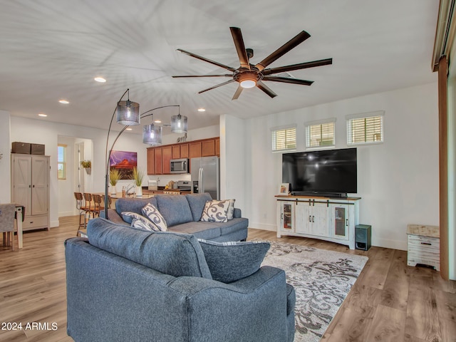 living room with light wood-type flooring, ceiling fan, and plenty of natural light