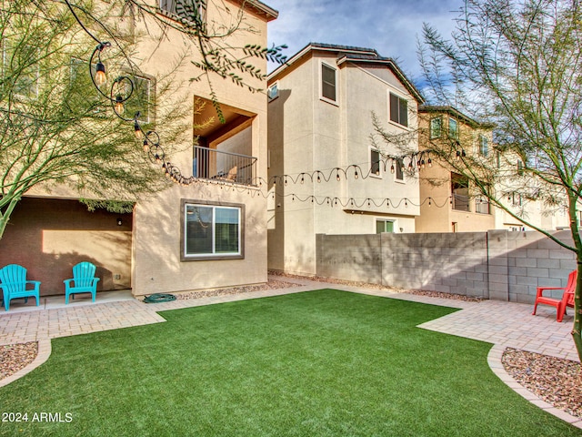 rear view of house with a lawn, a patio, and a balcony